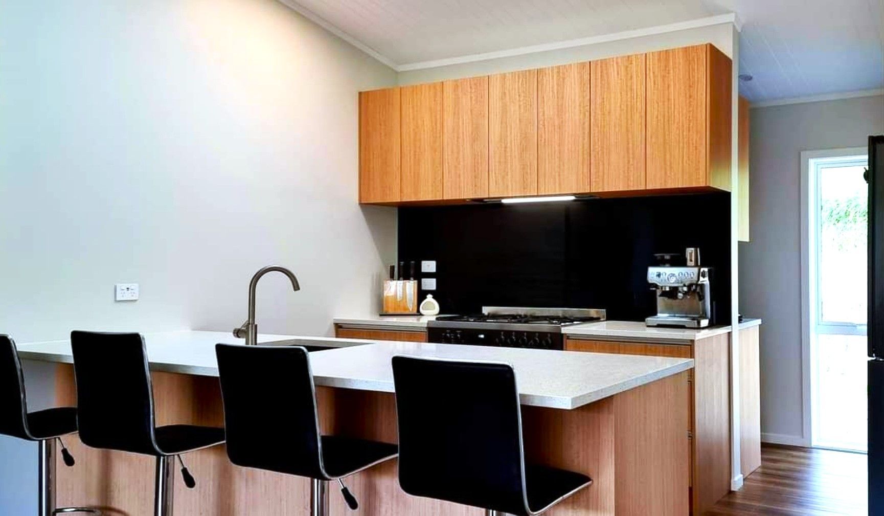 A kitchen with a stove , sink , and chairs.