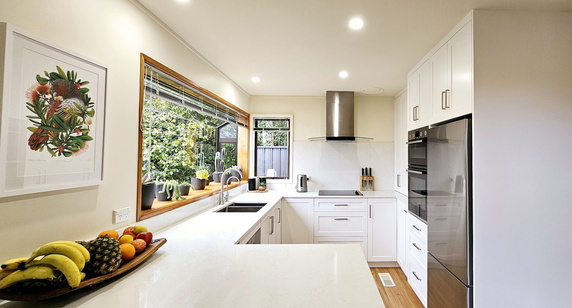 A kitchen with white cabinets and stainless steel appliances and a bowl of fruit on the counter.