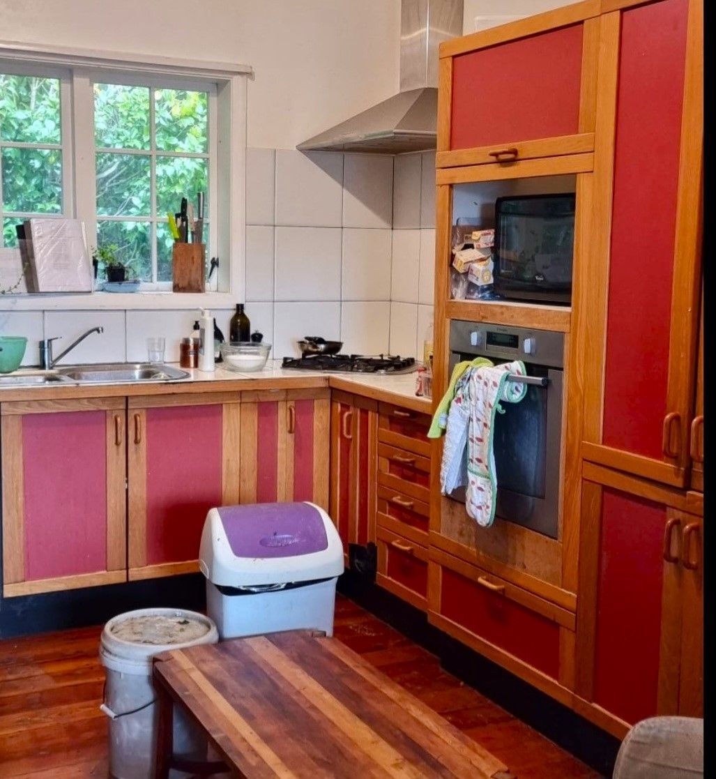 A kitchen with red cabinets and a purple trash can
