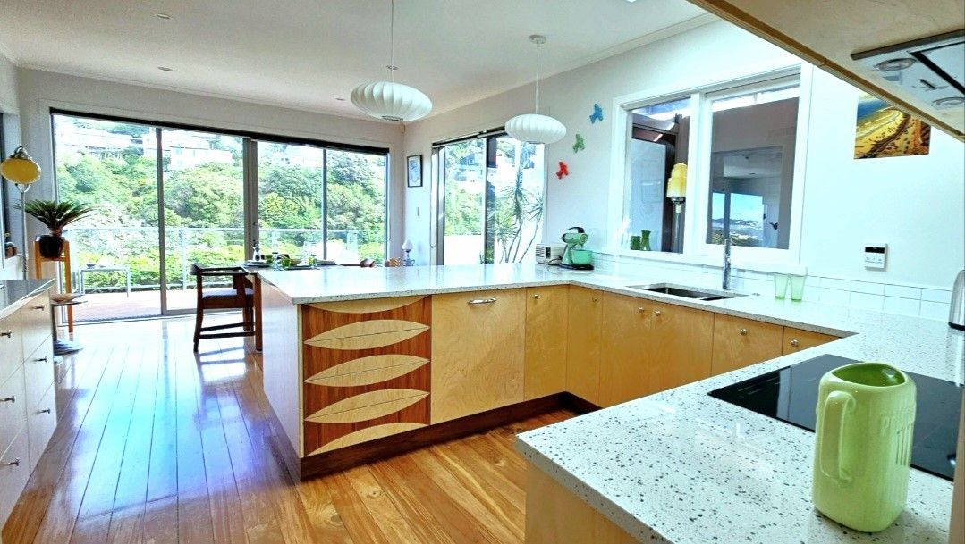 A kitchen with wooden cabinets , white counter tops , a sink , and a large island.