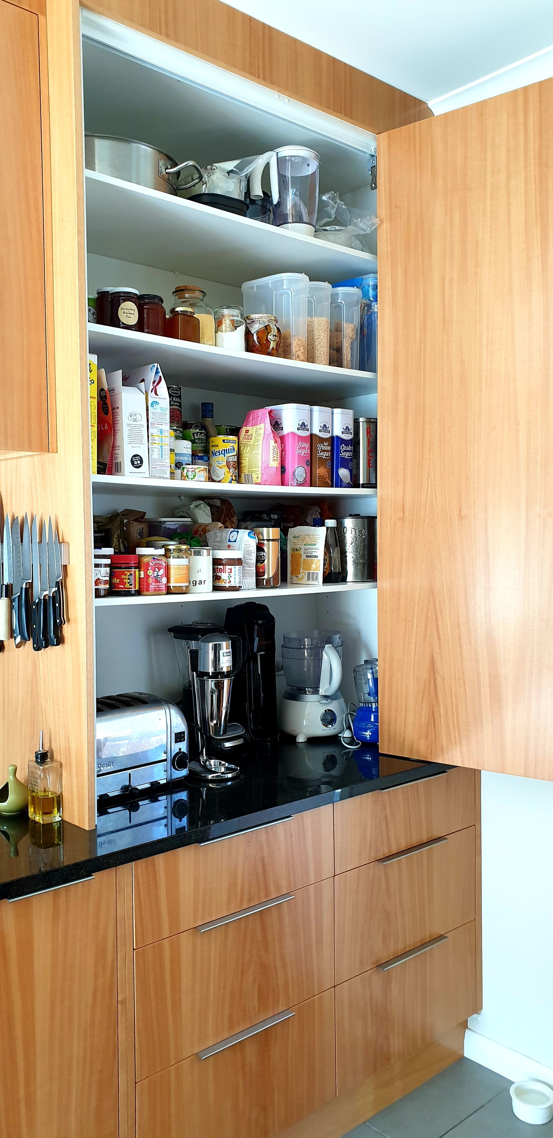 A kitchen with a pantry filled with lots of food and appliances.