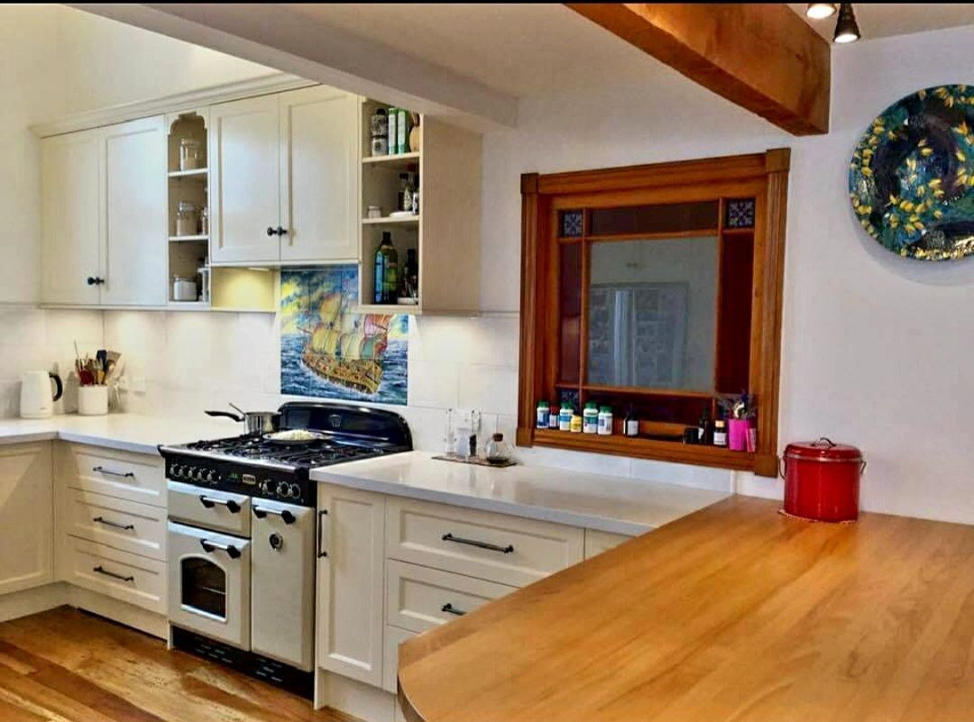 A kitchen with white cabinets a stove and a window