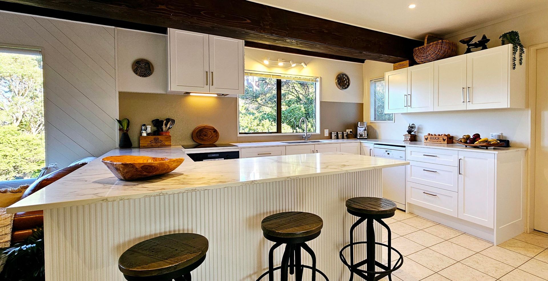 A kitchen with white cabinets and wooden stools