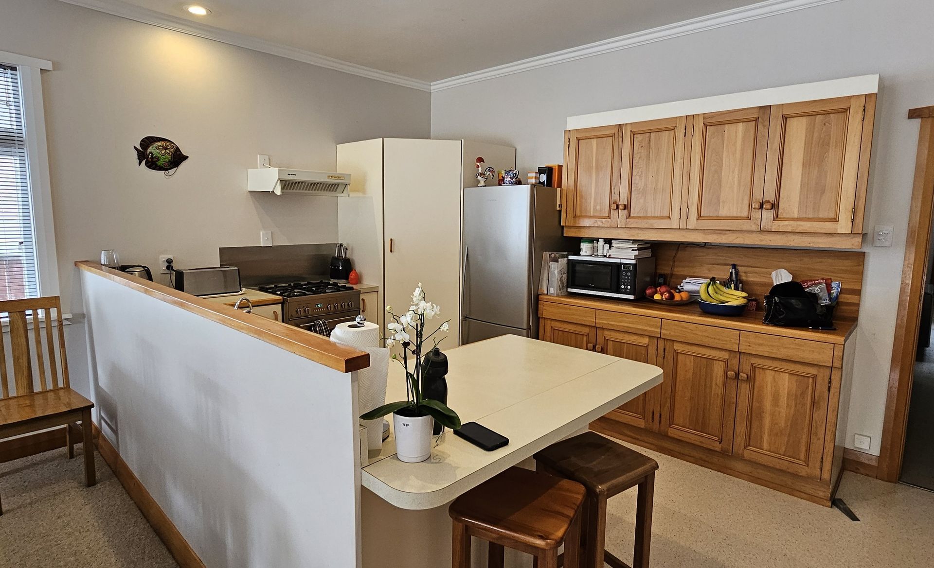A kitchen with a table and stools and a refrigerator