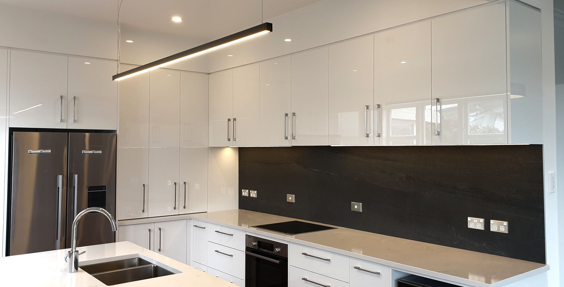 A kitchen with white cabinets , stainless steel appliances , a sink , and a refrigerator.