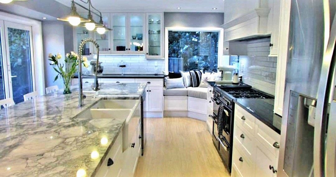 A kitchen with white cabinets , granite counter tops , stainless steel appliances and a large island.