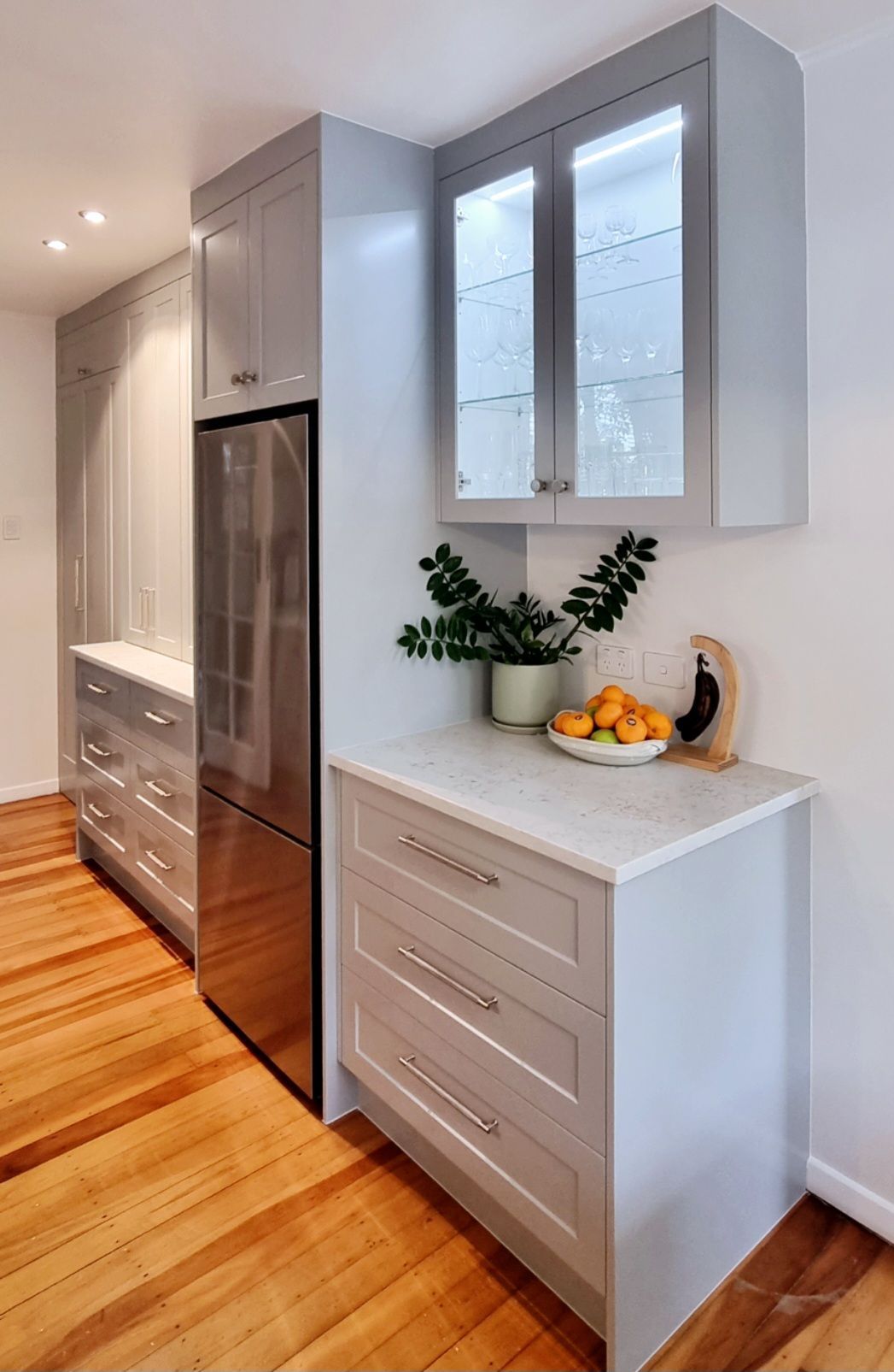 A kitchen with stainless steel appliances , wooden floors , white cabinets and a stainless steel refrigerator.