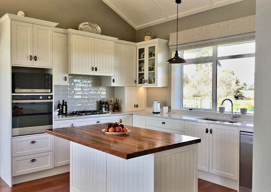 A kitchen with white cabinets and a wooden island.