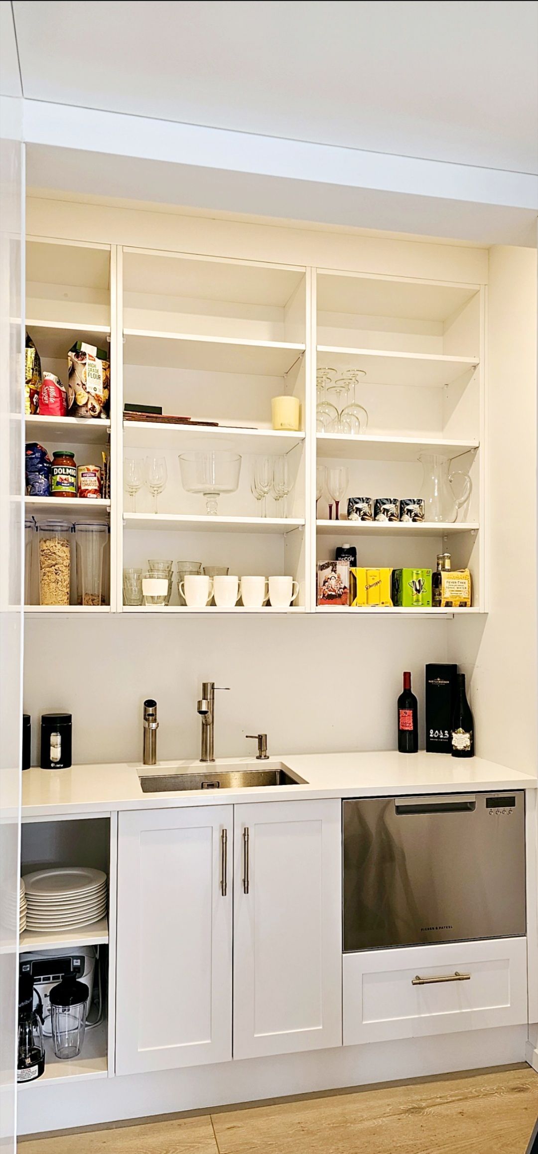 A kitchen with white cabinets , a sink , and shelves.