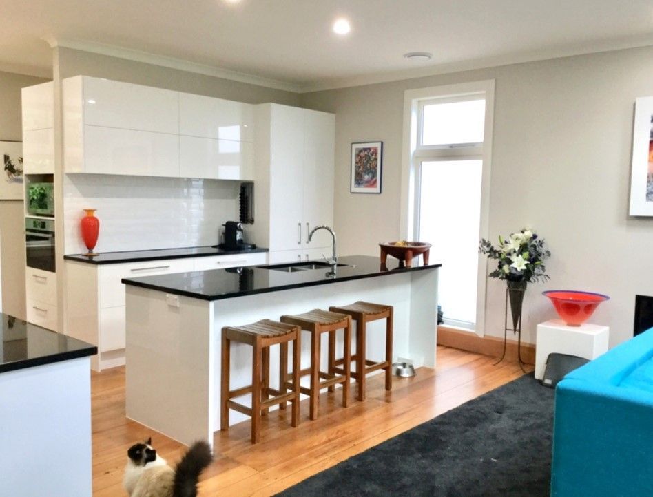 A cat is standing in a living room next to a kitchen.