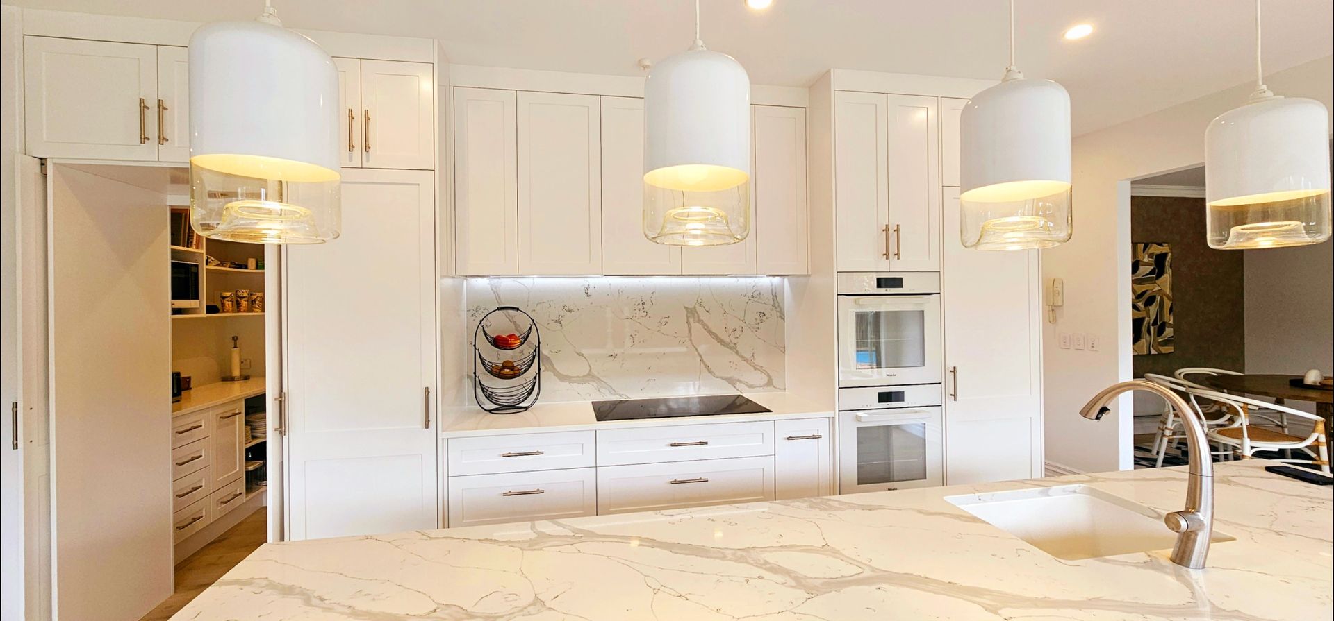A kitchen with white cabinets , a sink , and a stove.