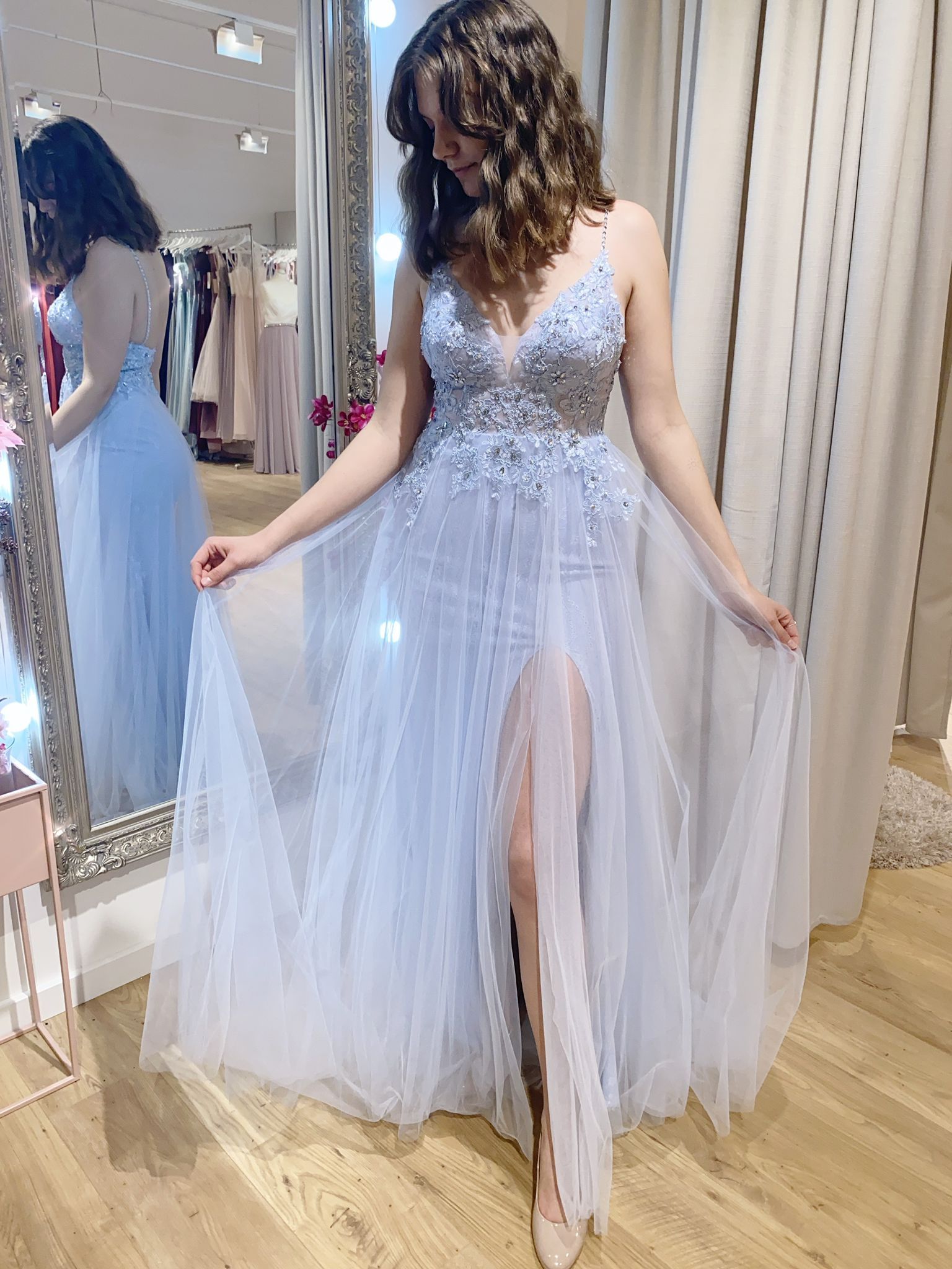 Eine Frau in einem hellblauen Kleid steht vor einem Spiegel.