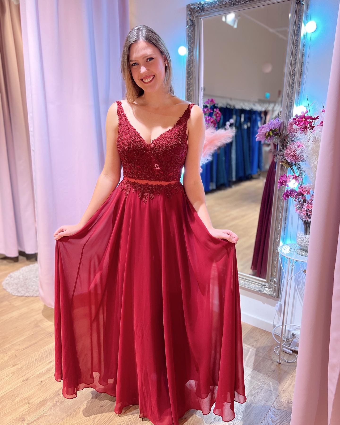 Eine Frau in einem roten Kleid steht vor einem Spiegel.