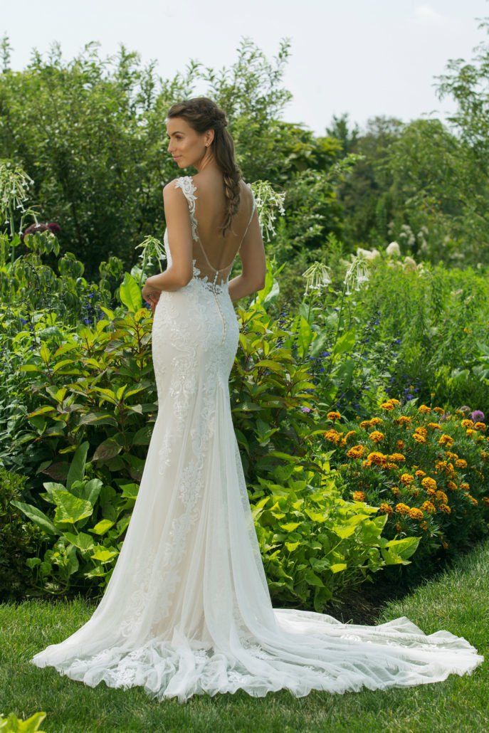 Eine Frau in einem Brautkleid steht in einem Garten.