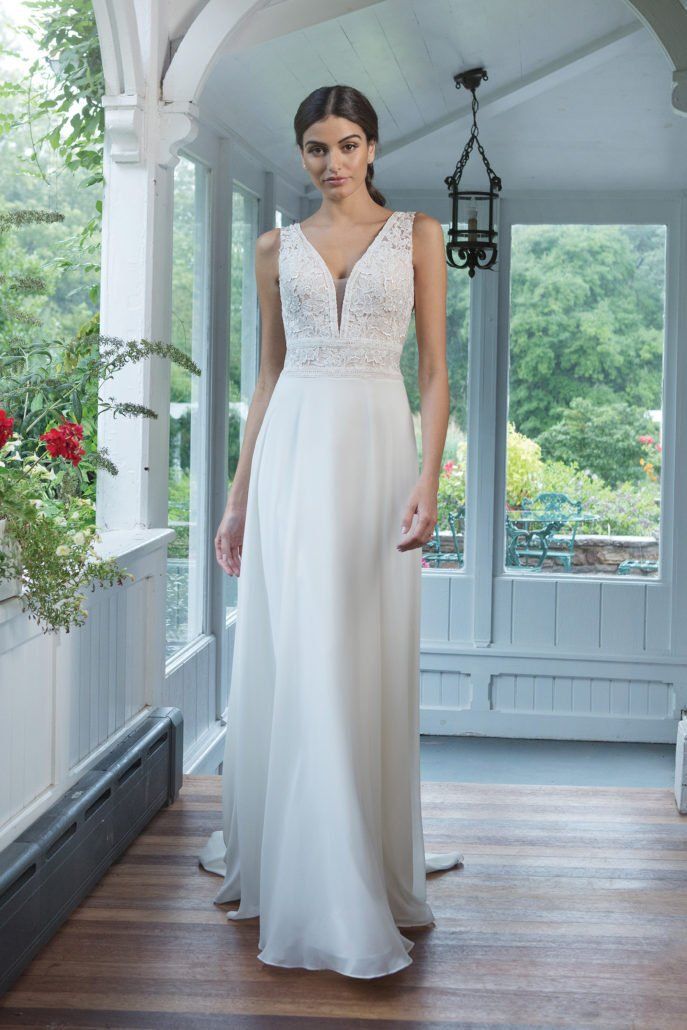 Eine Frau in einem weißen Brautkleid steht in einem Raum.