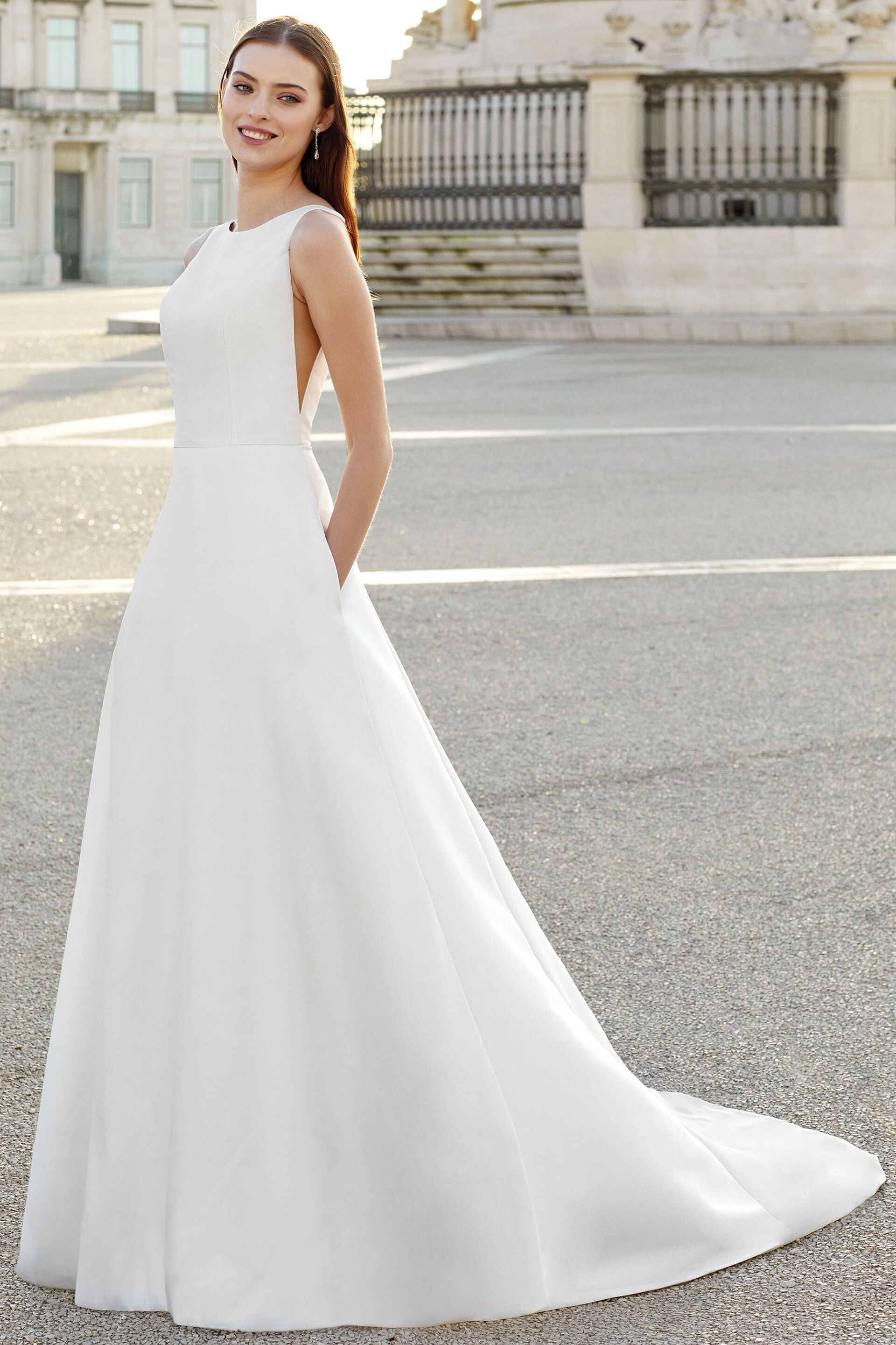 Eine Frau in einem weißen Brautkleid steht vor einem Gebäude.