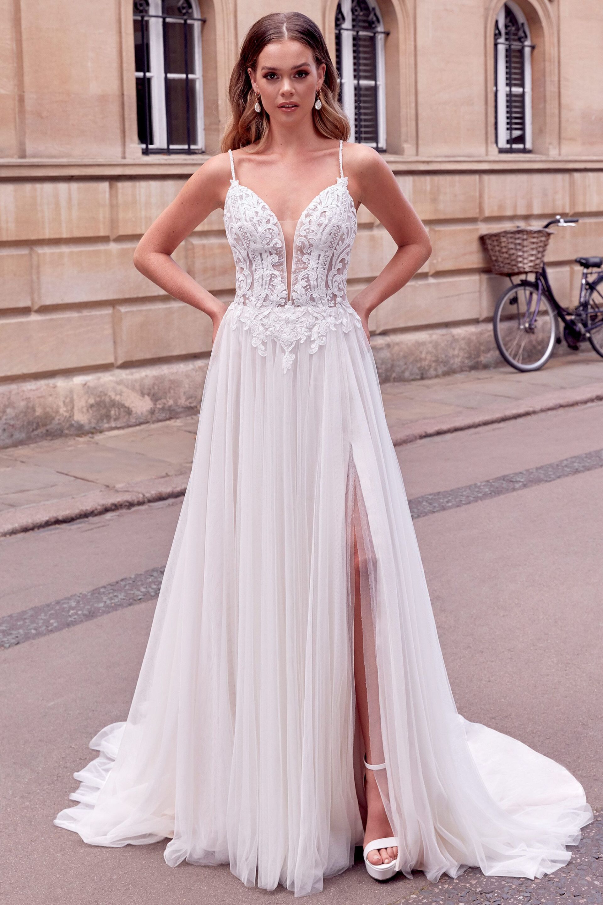 Eine Frau trägt ein weißes Brautkleid mit hohem Schlitz.