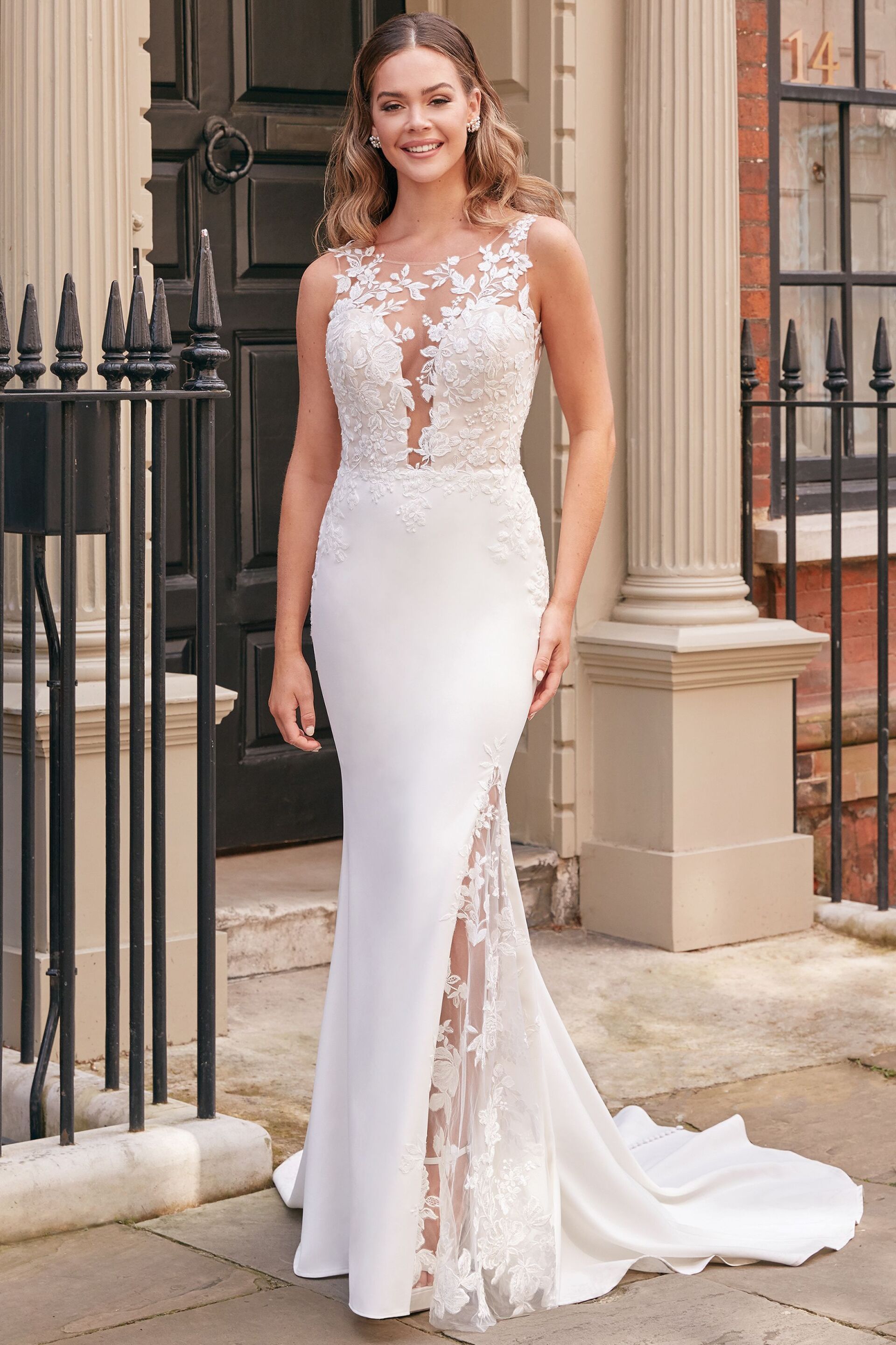 Eine Frau in einem weißen Brautkleid steht vor einem Gebäude.