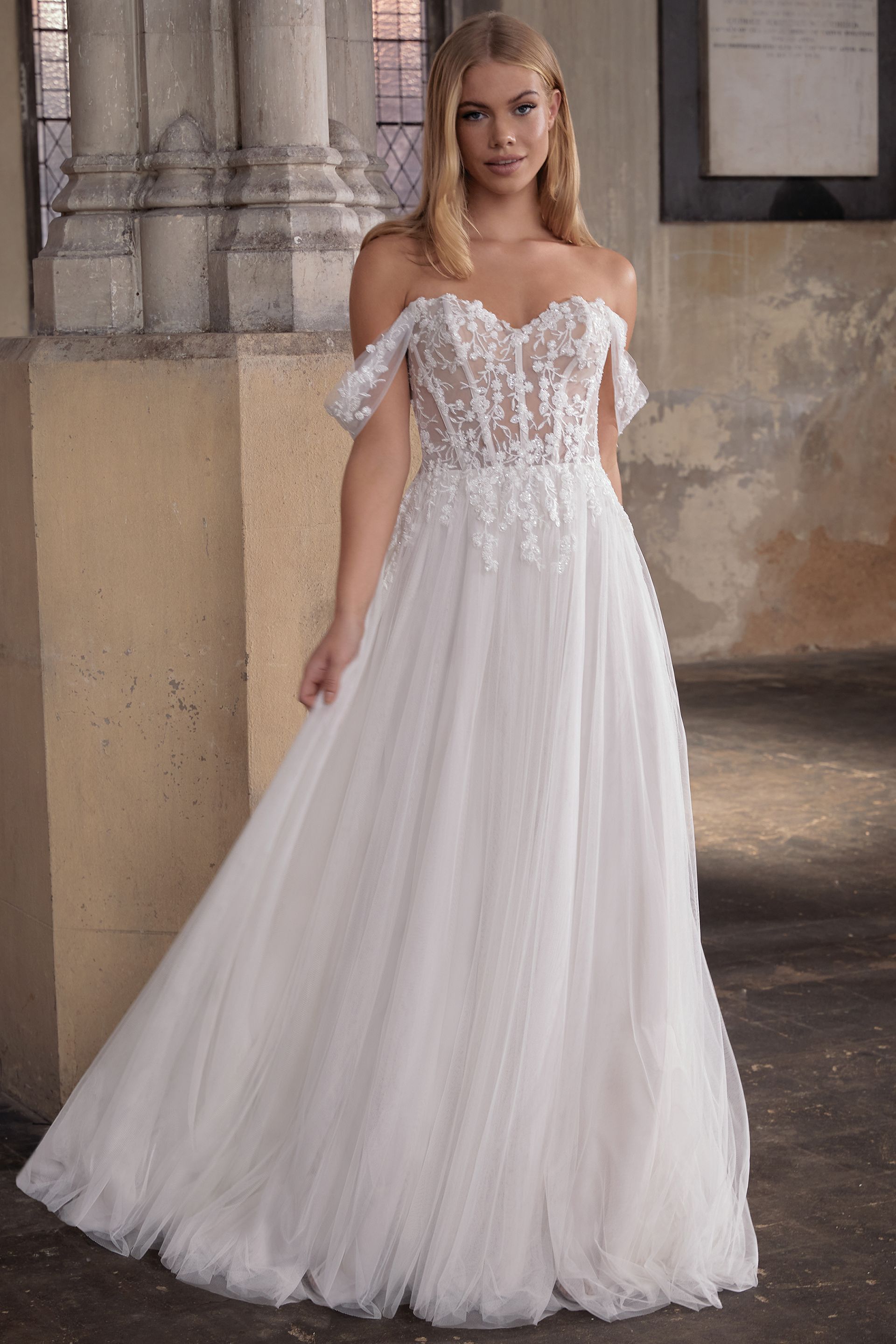 Eine Frau in einem weißen Brautkleid steht vor einem Gebäude.