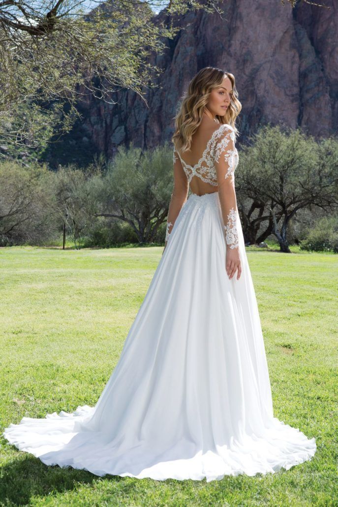 Eine Frau in einem weißen Hochzeitskleid steht auf einer Wiese.