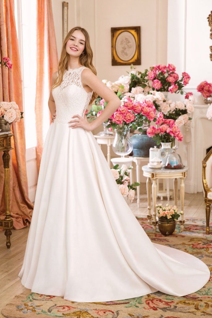 Eine Frau in einem weißen Brautkleid steht in einem Raum mit Blumen.