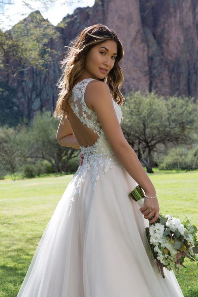 Eine Frau in einem Brautkleid steht auf einem Feld und hält einen Blumenstrauß in der Hand.