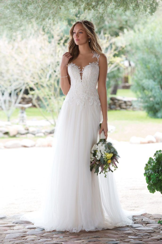 Eine Frau in einem weißen Hochzeitskleid hält einen Blumenstrauß.