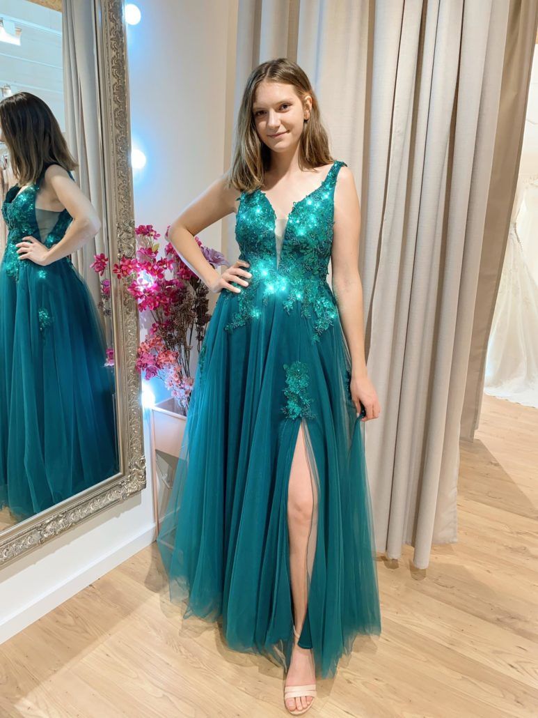 Eine Frau in einem grünen Kleid steht vor einem Spiegel.