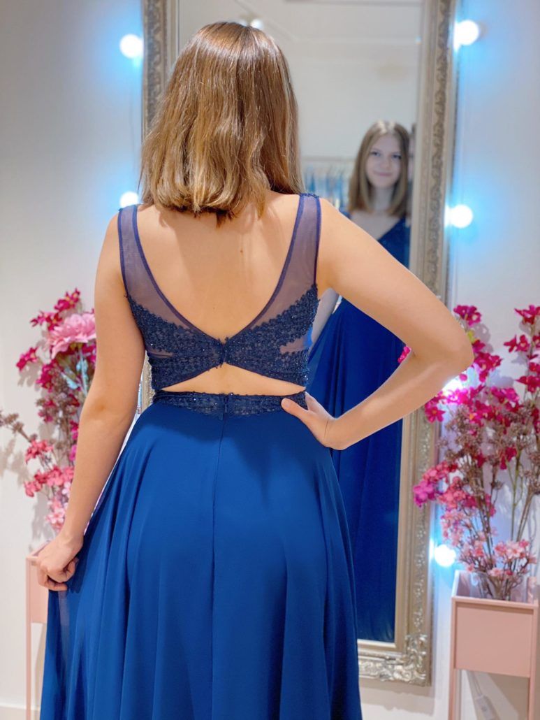 Eine Frau in einem blauen Kleid steht vor einem Spiegel