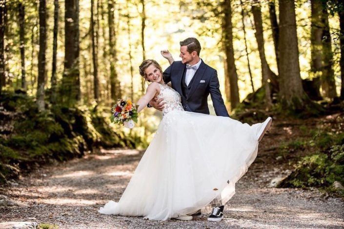 Eine Braut und ein Bräutigam posieren im Wald für ein Foto.