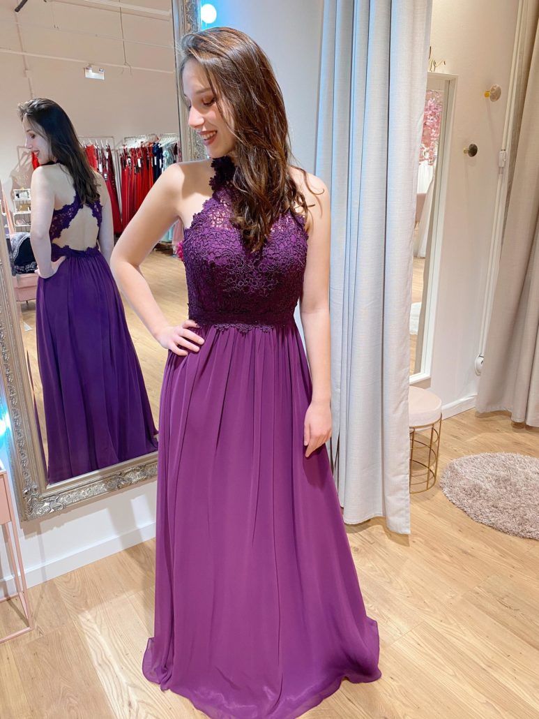 Eine Frau in einem lila Kleid steht vor einem Spiegel.