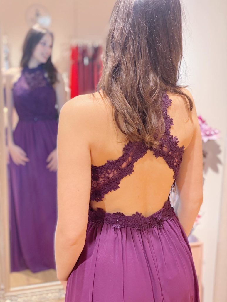 Eine Frau in einem lila Kleid steht vor einem Spiegel.