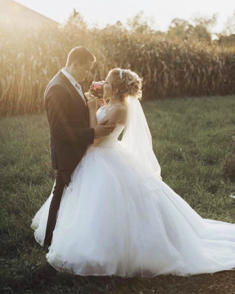 Eine Braut und ein Bräutigam stehen nebeneinander auf einem Feld.