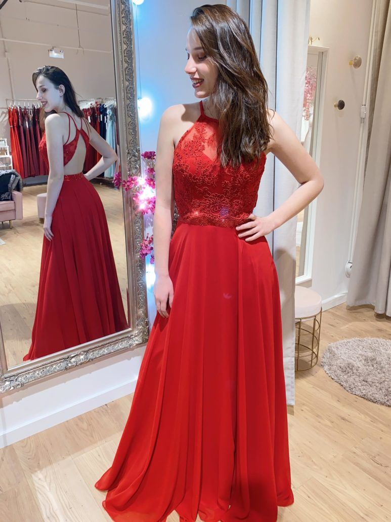 Eine Frau in einem roten Kleid steht vor einem Spiegel.