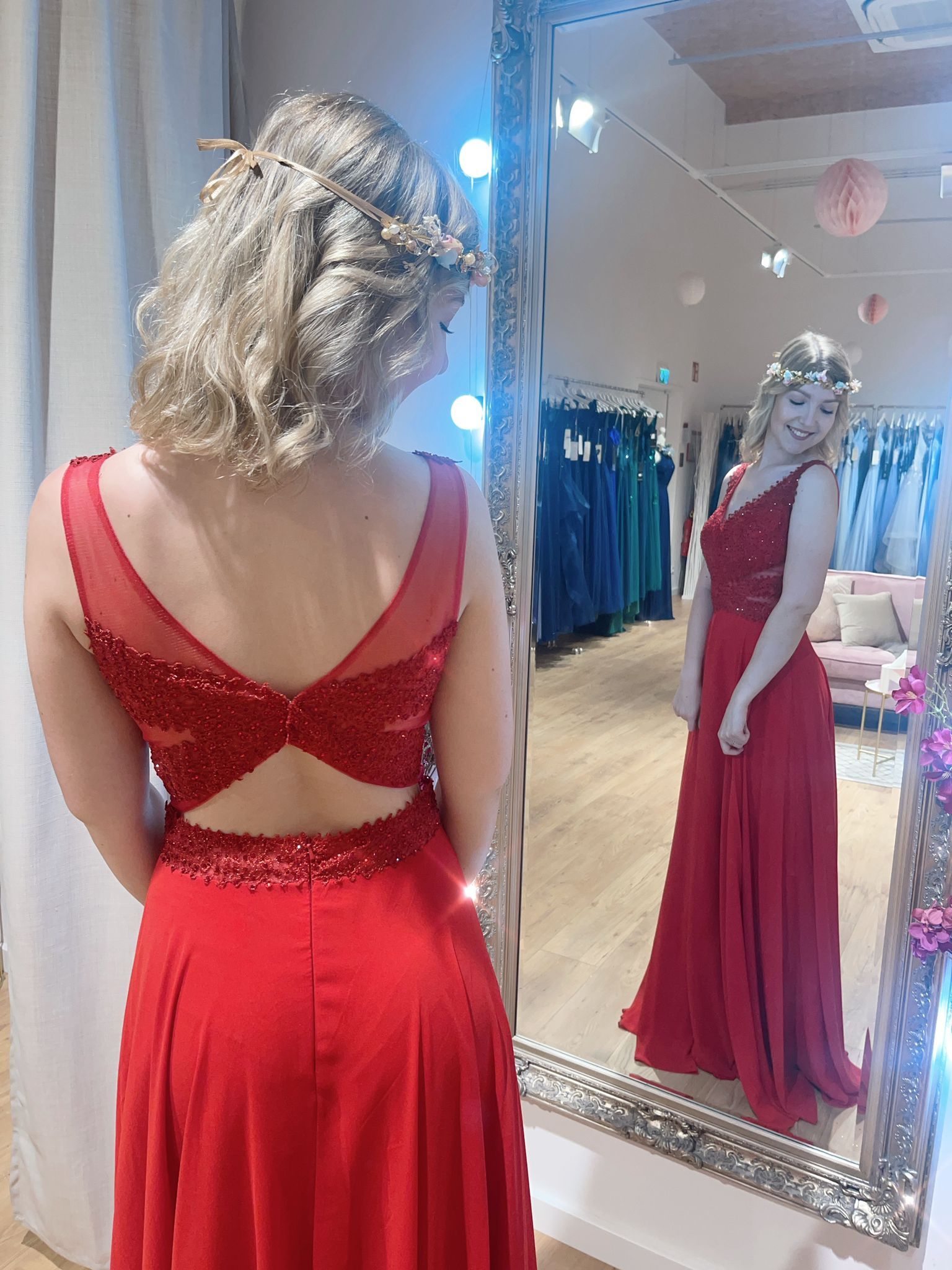 Eine Frau in einem roten Kleid steht vor einem Spiegel.