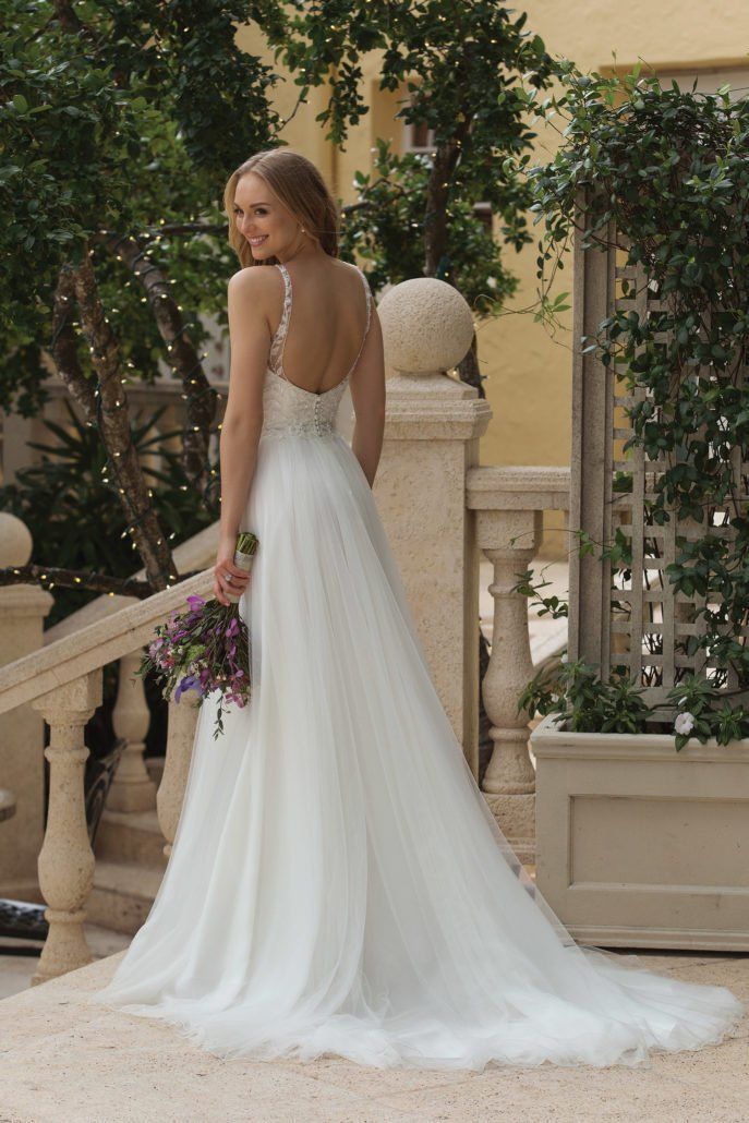 Eine Frau in einem weißen Hochzeitskleid hält einen Blumenstrauß.