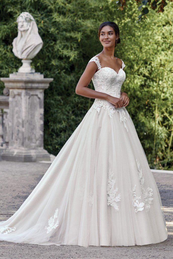 Eine Frau in einem weißen Hochzeitskleid steht vor einer Statue.