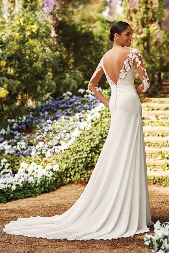 Eine Frau in einem weißen Hochzeitskleid steht in einem Garten.