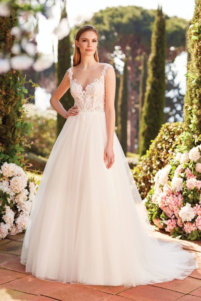 Eine Frau in einem weißen Hochzeitskleid steht in einem Garten.