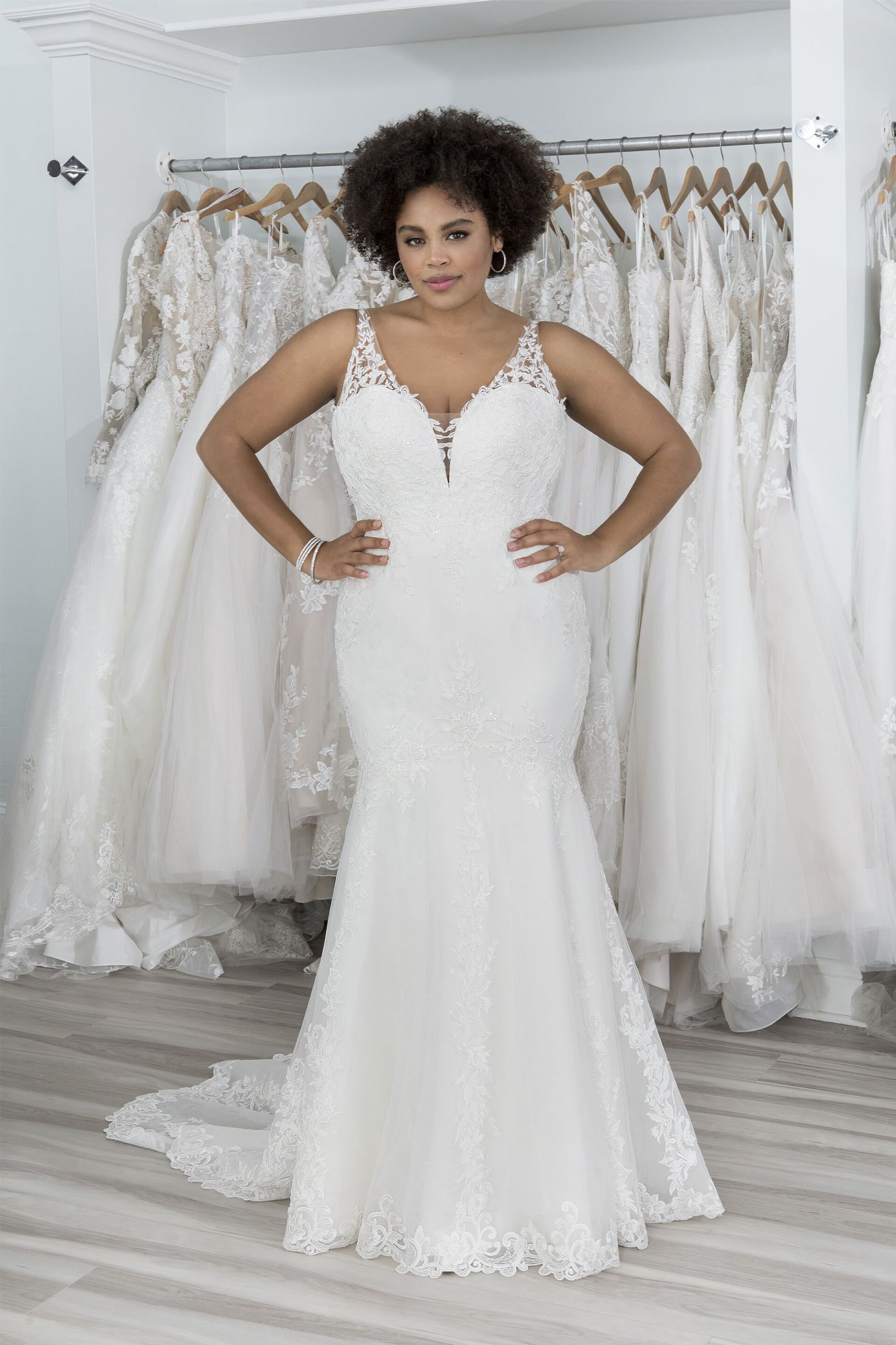 Eine Frau in einem weißen Brautkleid steht vor einer Reihe von Brautkleidern.