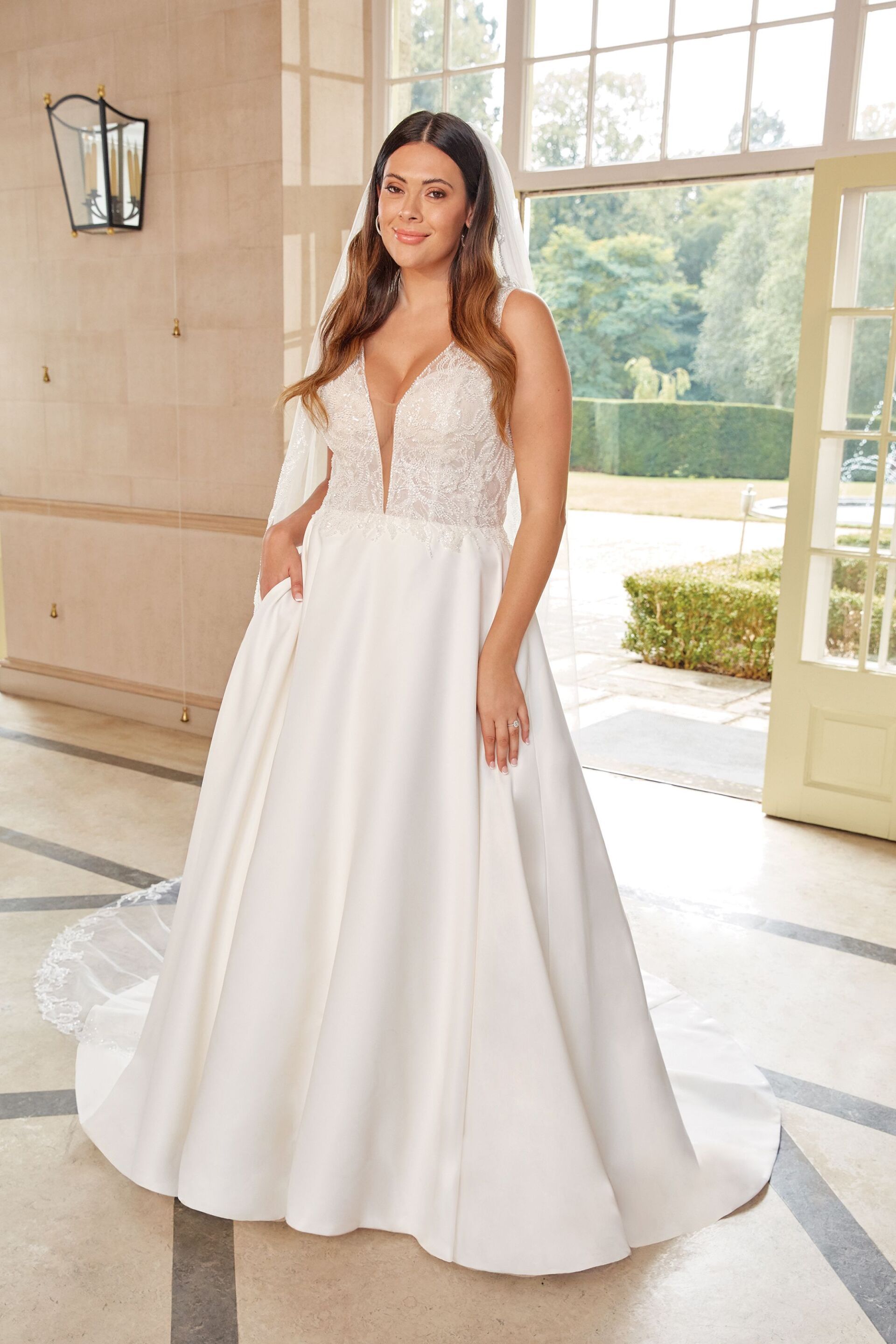 Ein Plus-Size-Model trägt ein weißes Brautkleid und einen Schleier.