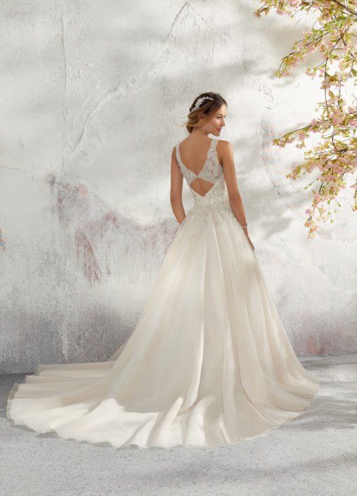 Eine Frau in einem weißen Hochzeitskleid steht vor einem Baum.