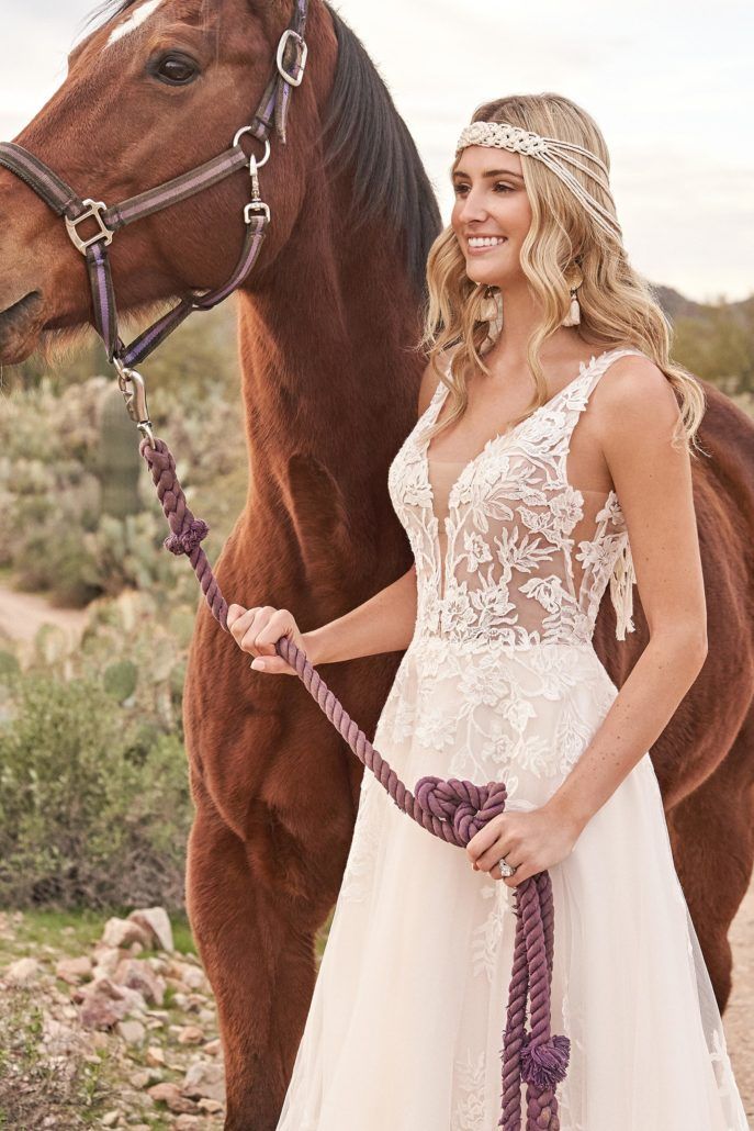 Eine Frau in einem Brautkleid steht neben einem braunen Pferd.