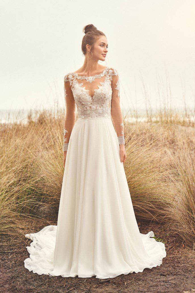 Eine Frau in einem weißen Hochzeitskleid steht auf einem Feld.