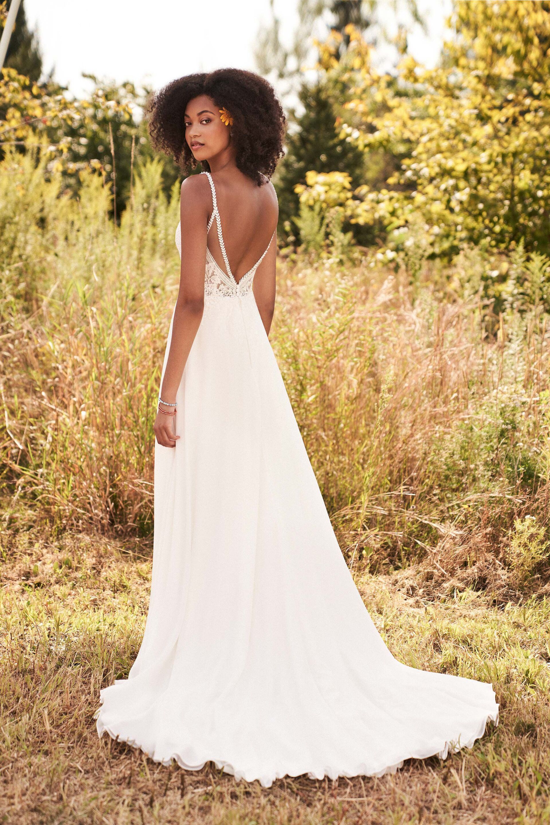 Eine Frau in einem weißen Hochzeitskleid steht auf einem Feld.