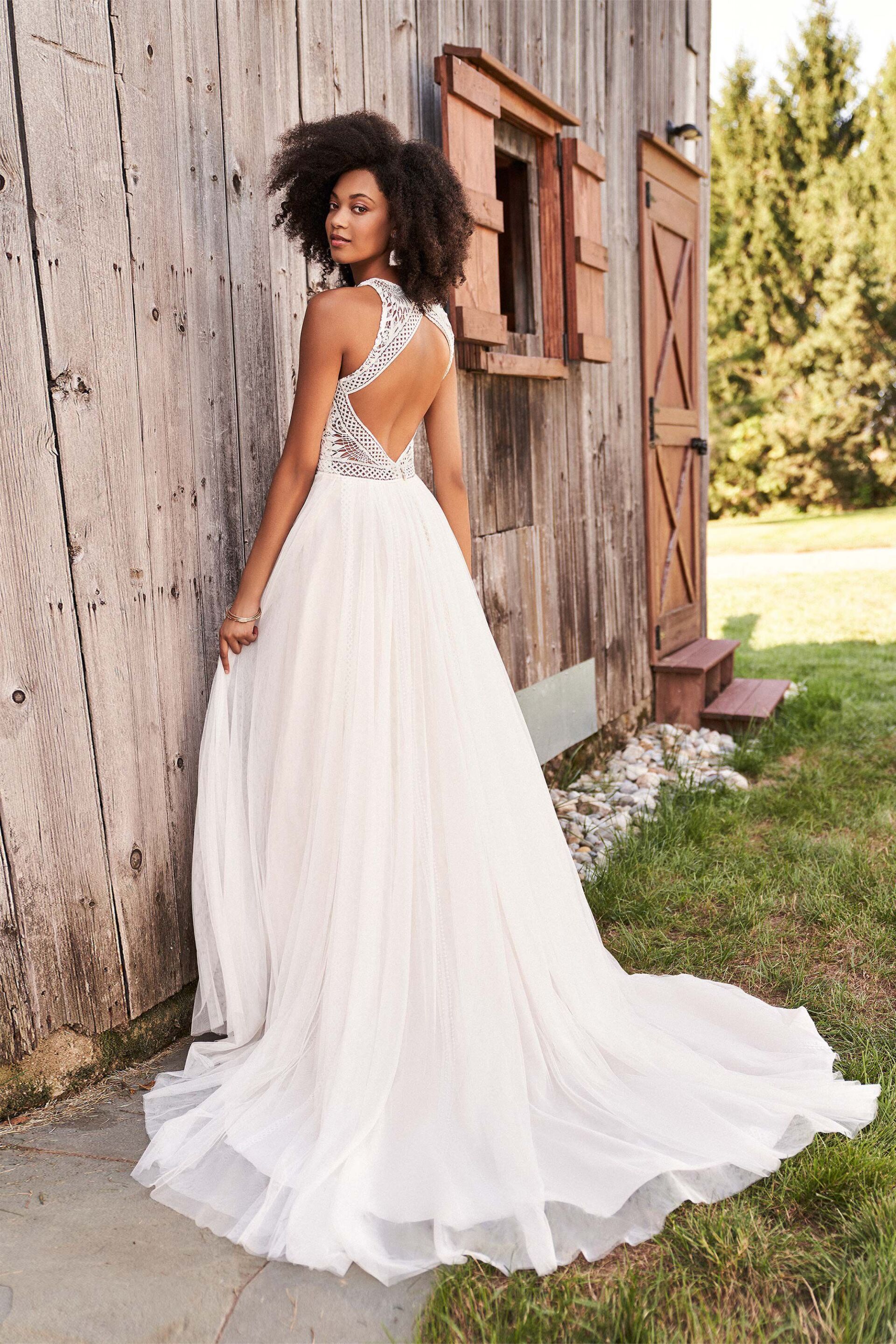 Eine Frau in einem weißen Brautkleid steht vor einem Holzgebäude.
