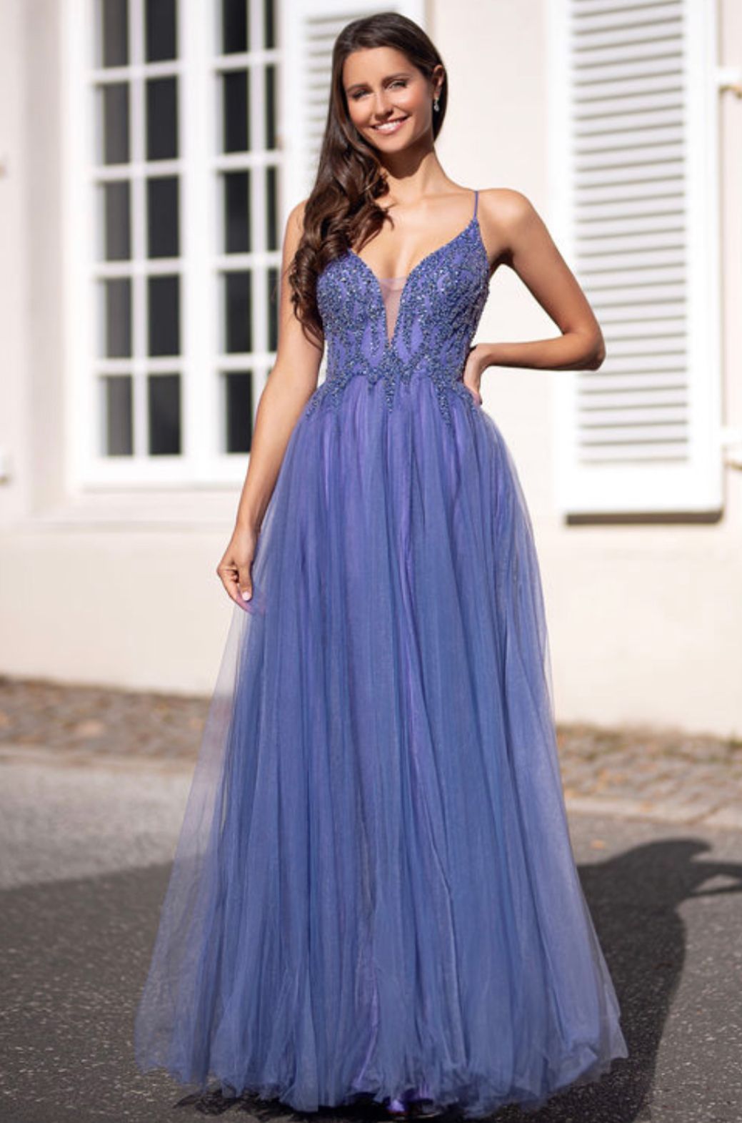 Eine Frau trägt ein lila Kleid und steht vor einem Gebäude.