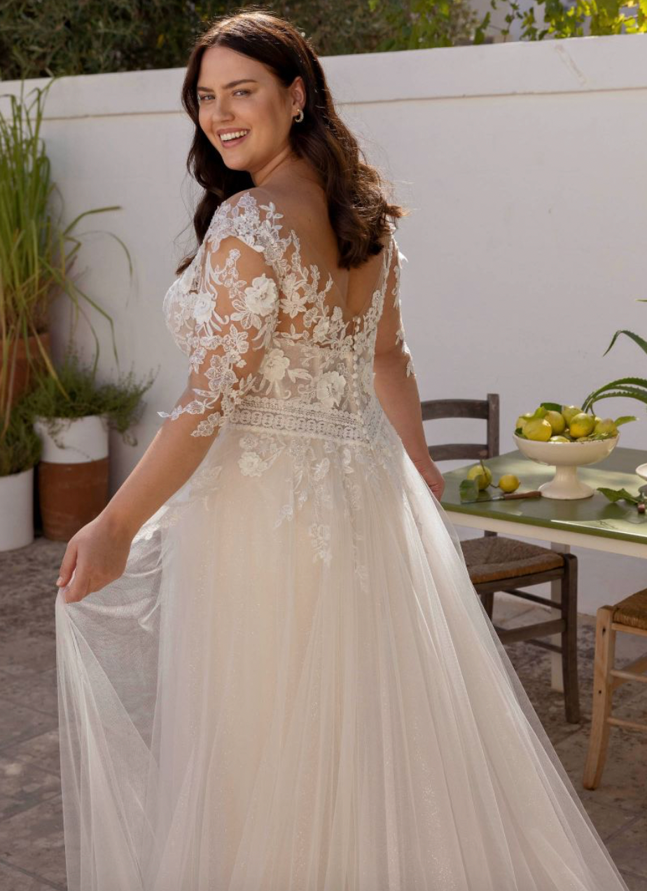 Eine Frau in einem Brautkleid steht vor einem Tisch.