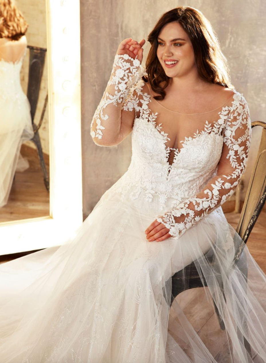 Eine Übergrößenfrau in einem Brautkleid sitzt vor einem Spiegel.