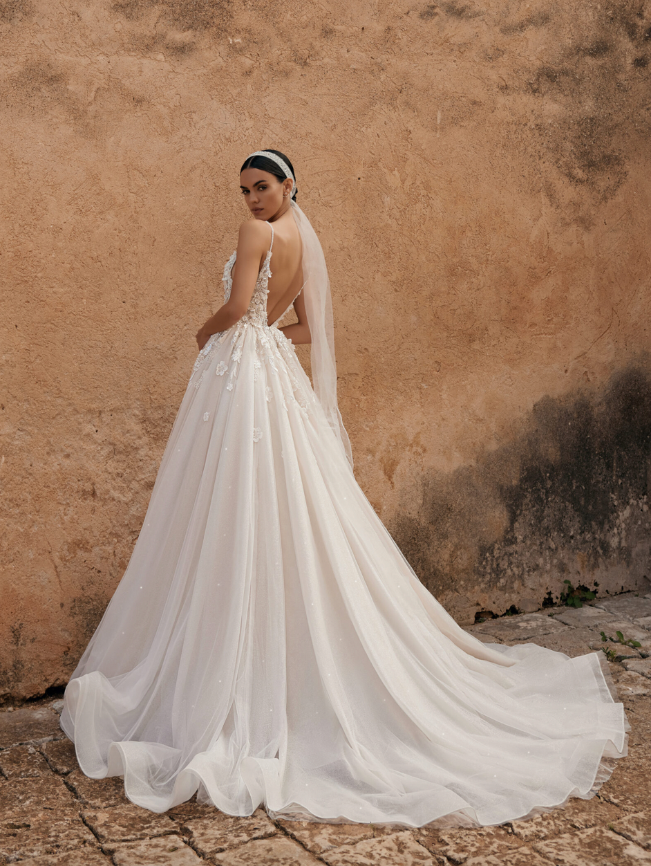 Eine Frau in einem Brautkleid und Schleier steht vor einer Wand.